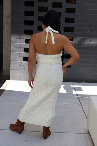 Woman in a white dress standing in front of a mirror in a bathroom.