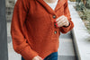 Person wearing a rust-colored cardigan with buttons, standing outdoors.