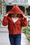 Person wearing a red hooded sweater in an outdoor setting