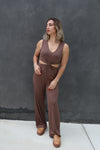 Woman wearing a brown jumpsuit against a dark gray background