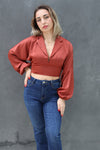 Woman wearing a red blouse and blue jeans against a gray background