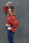 Woman wearing a red blouse and blue jeans against a gray background