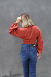 Person wearing a red blouse and blue jeans against a gray background