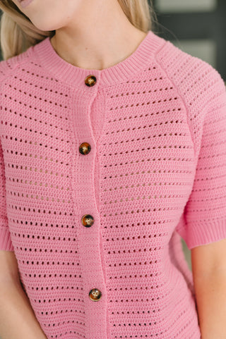 Pink crocheted cardigan with button details on a child