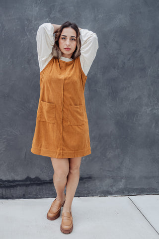 Woman wearing a mustard yellow dress against a gray wall