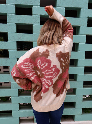 Person wearing a patterned sweater standing against a stack of green pallets.