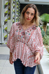 Woman wearing a floral blouse with a blurred outdoor background