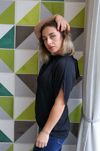 Woman posing against a geometric-patterned wall.
