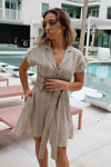 Woman in a striped dress standing by a poolside.