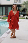 Woman in a red dress standing by a poolside.