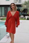 Woman in a red dress standing by a poolside.