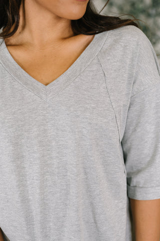 Close-up of a woman wearing a light heather gray short-sleeve V-neck t-shirt.