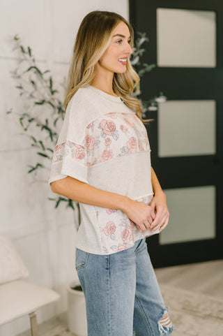 Woman wearing a floral blouse and jeans standing indoors.
