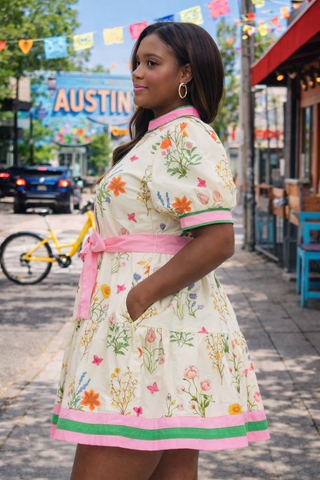Woman in a floral dress standing on a street with 'Austin' sign in the background