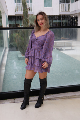 Woman in a purple dress standing in front of a glass door.