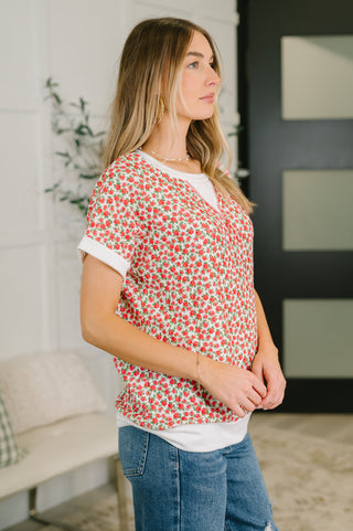 Woman wearing a red floral top and blue jeans indoors.