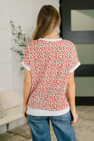 Woman wearing a red floral top and blue jeans in an indoor setting
