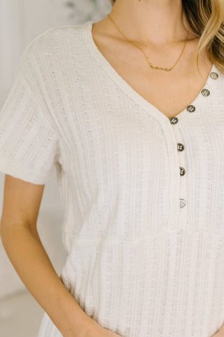 Close-up of a person wearing a white textured shirt with button details.
