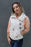 Woman wearing a white vest with pink star patterns against a gray background